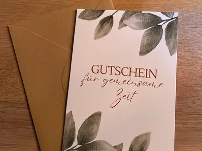 Vorschau: Klappkarte „Gutschein für gemeinsame Zeit“ mit Umschlag aus Kraftpapier auf einem Holztisch