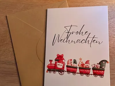 Vorschau: Klappkarte „Weihnachtszug“ mit Umschlag aus Kraftpapier auf einem Holztisch