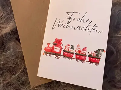 Vorschau: Klappkarte „Weihnachtszug“ mit Kraftpapier-Umschlag auf einem hellen Fell