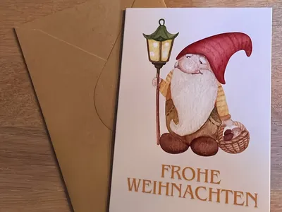 Vorschau: Klappkarte „Wichtel mit Laterne“ mit Umschlag aus Kraftpapier auf einem Holztisch